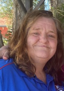 Smiling person in blue shirt outdoors.