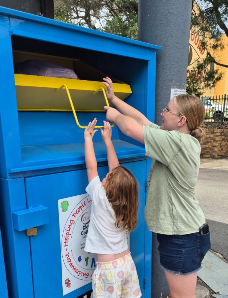 Mother and child donating clothes to charity bin.