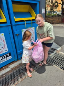 Children donating clothes at charity bin, Australia.