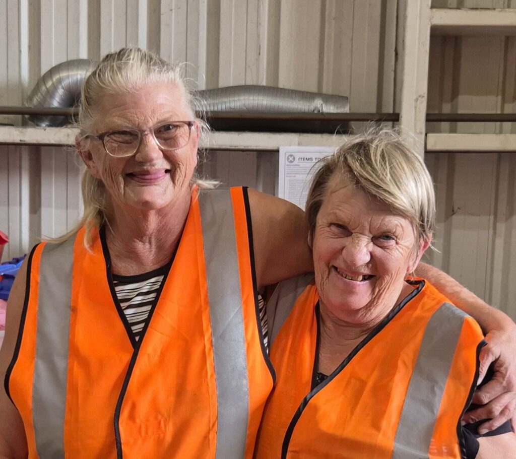 Two women in safety vests smiling together.