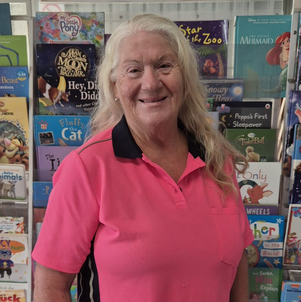 Smiling woman in pink shirt before children's books