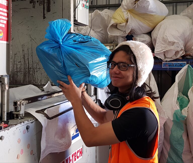 Worker loading bag into textile recycling machine