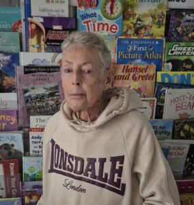 Elderly woman before colourful children's books display